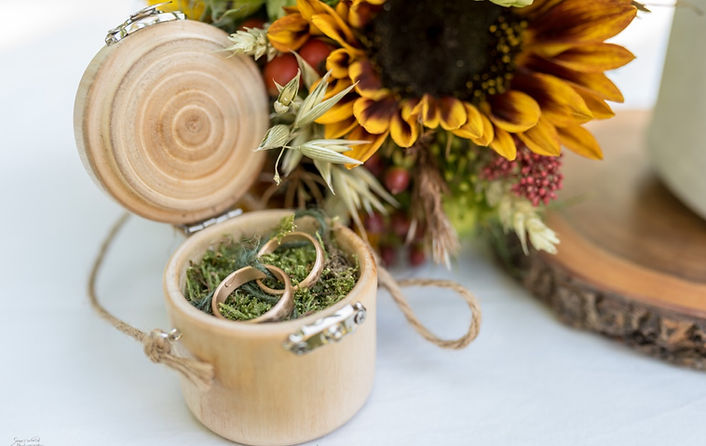 Ringe in Holzschartulle und Sonnenblume im Hintergrund