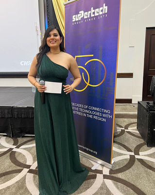 Karnica Karda hosting the Súper Tech Corporate Event in Dubai, wearing a green gown.