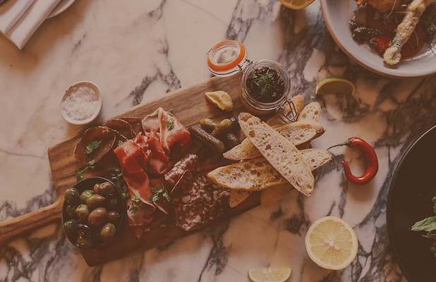 Charcuterie board arranged on marble table with olives, cured meats, bread, and dips at a private table setting in Leesburg, Virginia.
