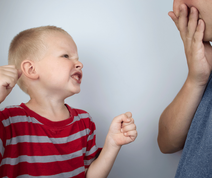 Un petit garçon métisse assis à table prêt à manger une glace.