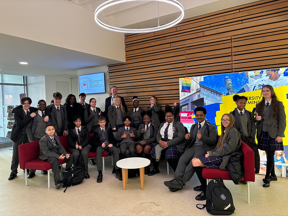Group posed in a bright lobby, seated and standing around white tables, with colorful wall art behind them