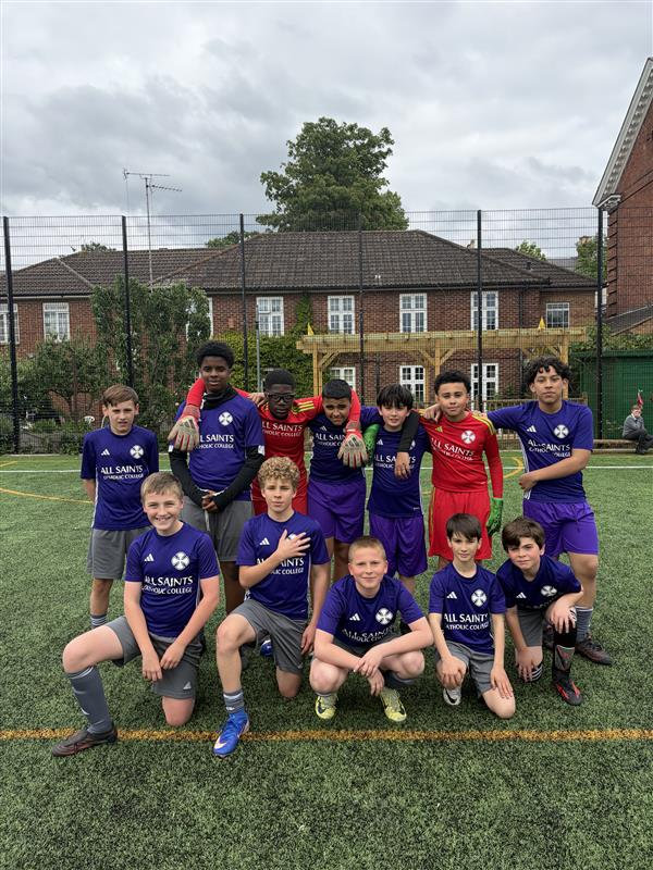 Youth soccer team posing on a turf field, wearing blue and red uniforms, with houses in the background