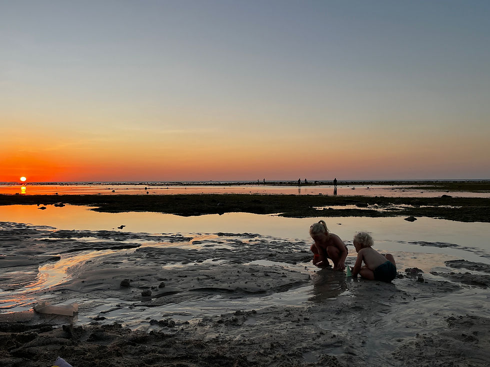 kinderen spelen op strand bij ondergaande zon