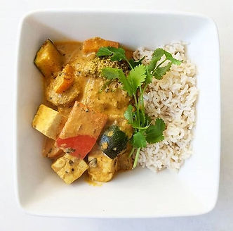 A square bowl with a tofu and vegetable curry with rice