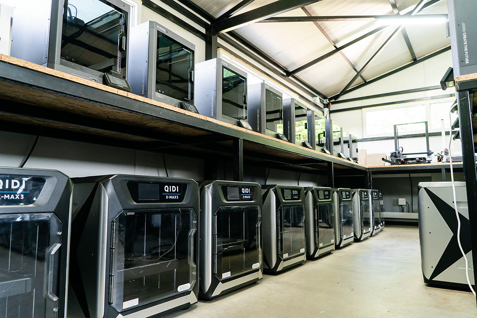Row of enclosed FDM printers at floor level with a second row on the shelf above