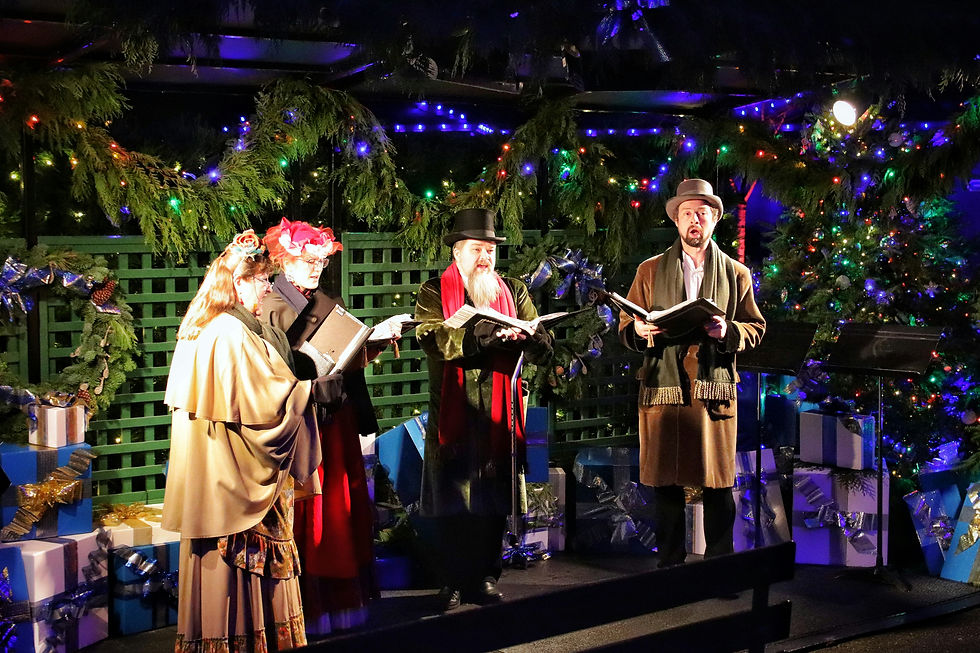 Carol singers in vintage attire perform under festive lights, surrounded by decorated greenery and presents. Moods are joyful and atmospheric.