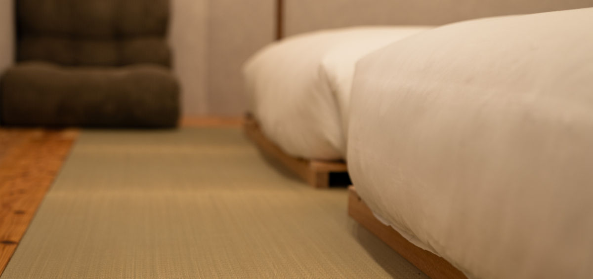 Modern bedroom with low platform bed, soft lighting, and dark green sofa.