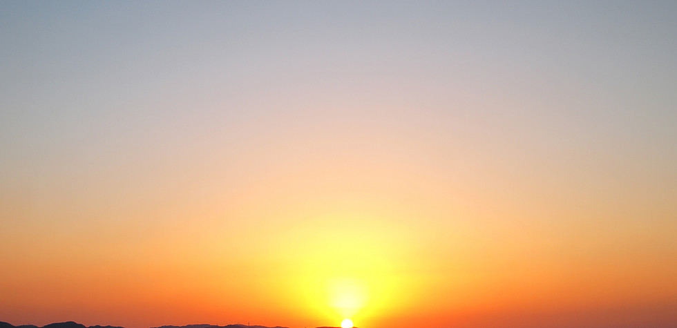 海に沈む鮮やかな夕日と、その向こうの山々。