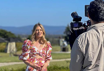 Camera operator filming a presenter outdoors