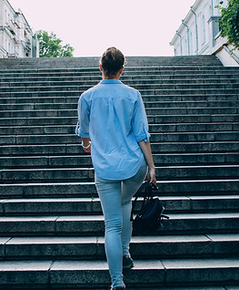 Person walking up the stairs outside wearing denim and looking confiden after therapy for grief and loss in Denver, CO. You can get help for loss and grief in Englewood, CO for therapy and counseling in the Denver area at Catalyss Counseling 80209 and 80210