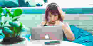 Woman lies in a large blue beanbag chair with her laptop open while searching for an online therapist. Let Catalyss Counseling be your online counseling resource for therapy in Colorado located in Englewood CO.