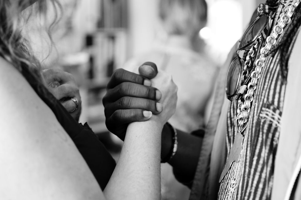 A clinical supervisor and supervisee holding hands for support for people of color with clients and in their relationship