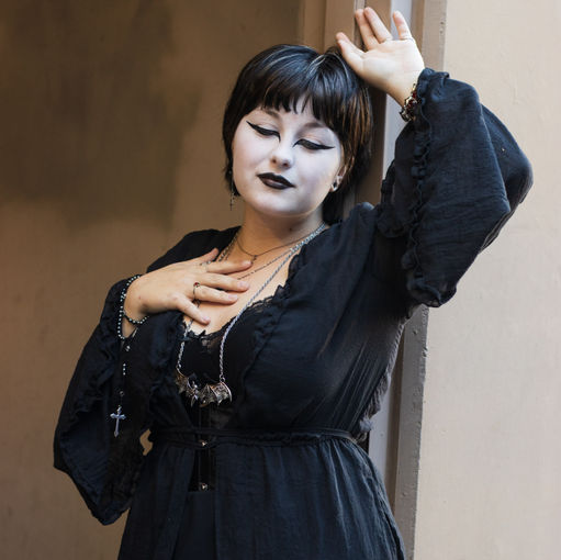 Gothic woman leaning up against doorway.
