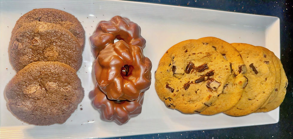 Three chocolate cookies, two chocolate-covered pastries, and three chocolate chip cookies on a white tray, set on a dark surface.