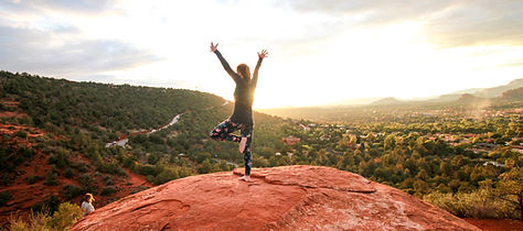 A woman in the Red Rocks arms extended at sunset on a Sedona yoga retreat.