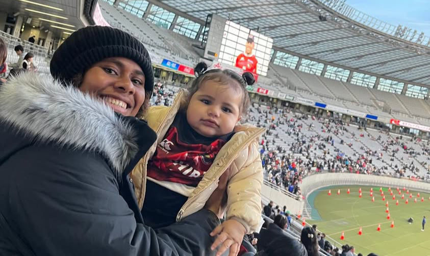 Neihamu holding her niece at the 2024 League One final in Tokyo as Naikabula receives his Player of the Match award
