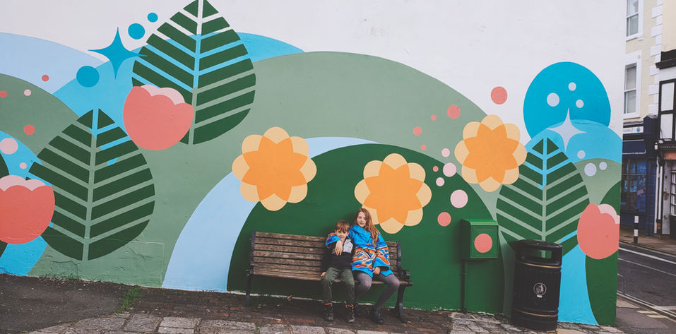 A bright mural with giant leaves, pink tulips and orange and yellow flowers, blue arches and stars and circles