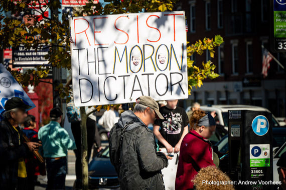 A protester holding a sign that says "resist the moron dictator"