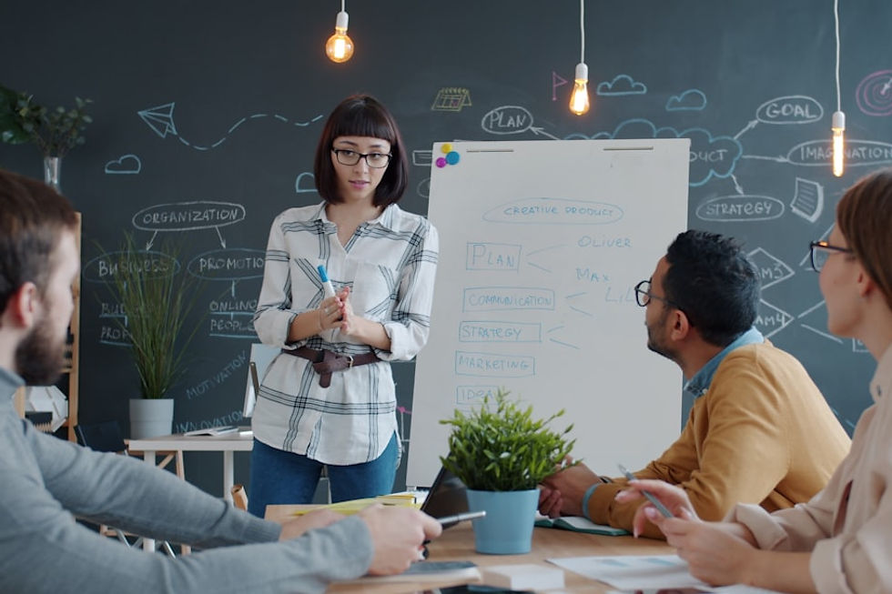 Woman presents to colleagues at a whiteboard meeting.