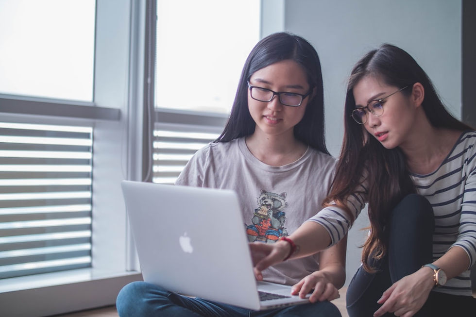 two women discussing each other while looking on laptop