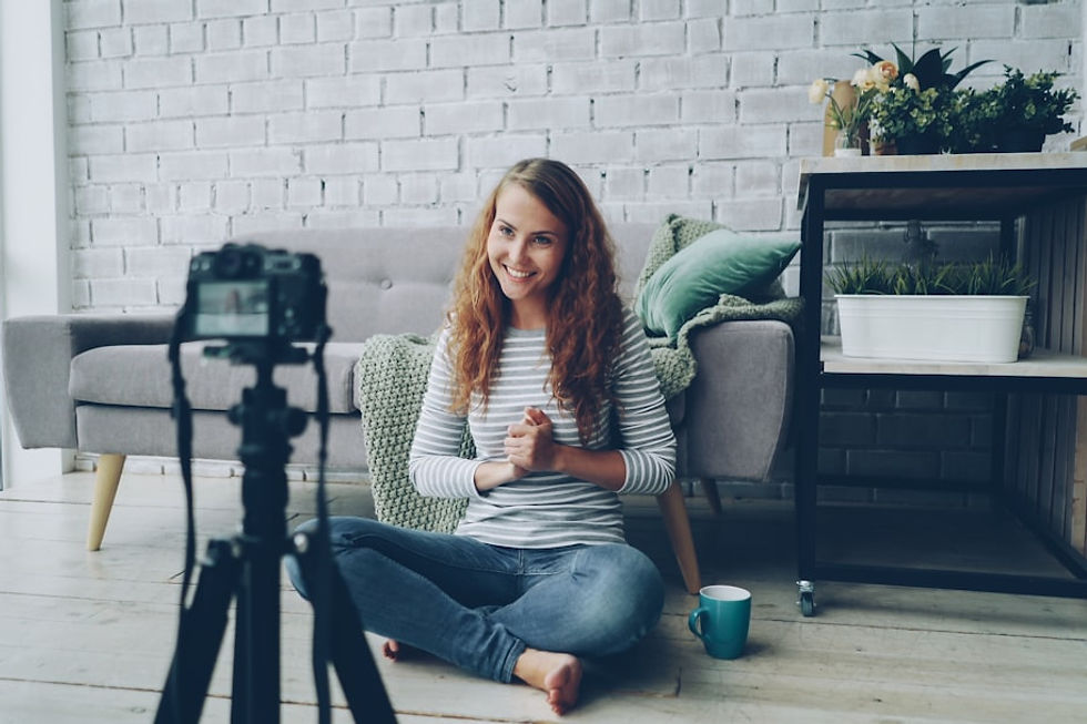 Woman sitting on floor filming herself with camera.