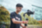 Young man smiling while operating a camera gimbal