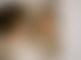 Mulher sorridente se olhando no espelho e tocando o rosto suavemente, refletindo bem-estar com a própria imagem.