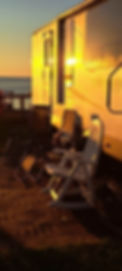 Roulotte de Camping avec des chaises dehors.