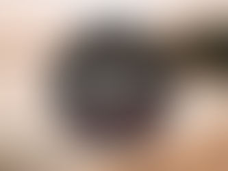 Lämminhenkinen rippikuvaus Lappeenrannassa. Nuori rippityttö hymyilee ja kävelee paljain jaloin hiekkarannalla järven rannalla vaaleanpunaisessa juhlamekossa. Hän pitää kenkiään kädessään. Taustalla näkyy tyyni järvi, metsää ja laskeva aurinko.