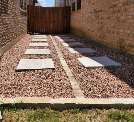 concrete stepping pads with brown rocks and stone edges in a side yard Fort Worth, Tx.