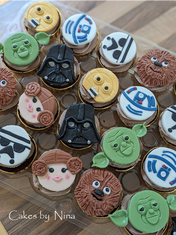 Star Wars themed cupcakes with character faces like Yoda and Vader.