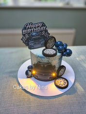 White base colour single tier cake, with an light up car and fondant wheels and ball decorative balls and an personalised topper