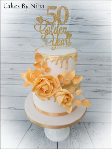 Two-tiered cake with gold roses and "50 Golden Years" topper.