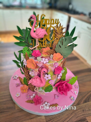 Bring a touch of tropical elegance to your celebration with this vibrant, handcrafted flamingo cake. Designed to make a real statement, this tall 6-inch cake features two individually handmade flamingos surrounded by an abundance of handcrafted tropical flowers and lush foliage.