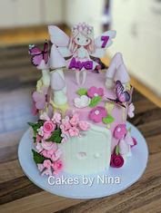 Beautiful pink girly fair cake covered in sugar flowers and a sweet fairy on the top