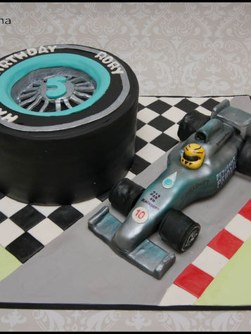 Vehicle cake with tire and race car on a checkered surface.