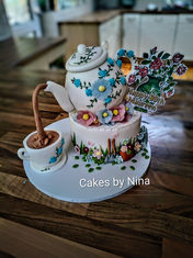 3d edible teapot that is dripping tea out of its spout into an edible tea cupcake, with sugar flowers, and gardening decorations