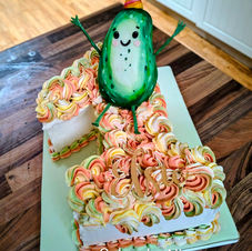 A large number one with buttercream swirls and an 3d edible cartoony pickle on top