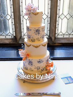 Four tier cake with a white background and beautiful wedgewood design and orange and blush pink sugar flowers