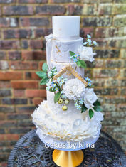 Stand out ruffle bottom cake with gold leaf picture frame and gorgeous sugar forget me nots and white sugar flowers with multi texture effect