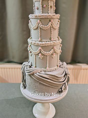 Four tier wedding cake with a background colour of blue grey, with tiny pink sugar roses, and sugar swags and sugar bow