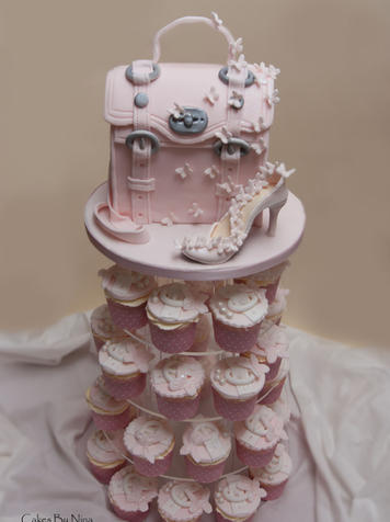 Pink purse cake on top a tower of frosted cupcakes