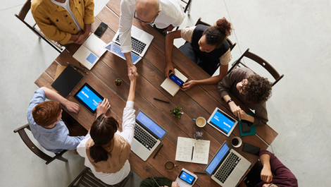 A team collaborating and communicating around a table with laptops.