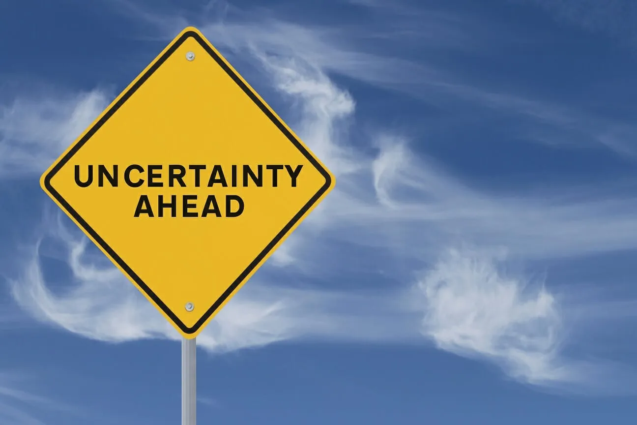 Picture of a square yellow street sign that says uncertainty ahead