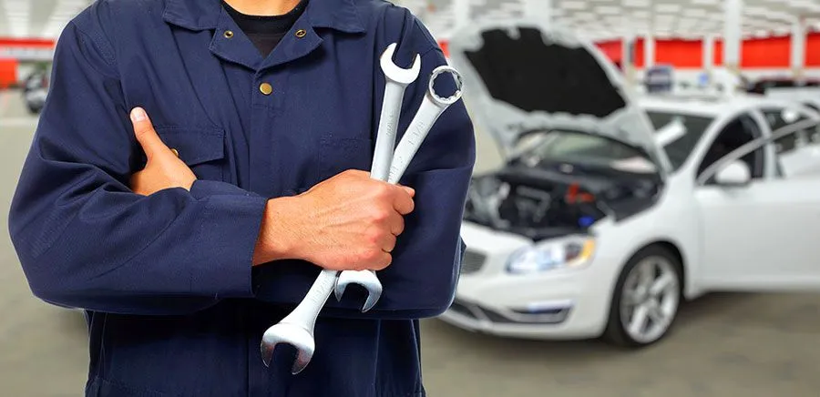 Picture of a mechanic folding some tools in front of a white care