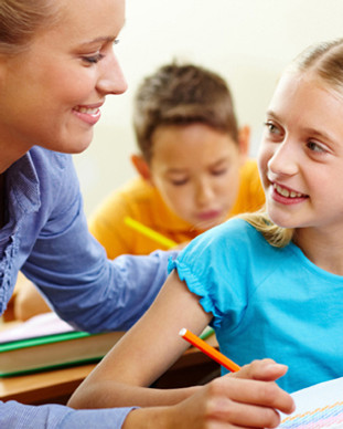 woman smiling at young girl student holding pencil wearing blue blouse