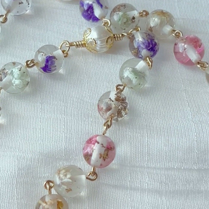Thumbnail: rosary multicolour floral resin beads, gold-wrapped flower beads, Marian centerpiece, and pearl-accented crucifix