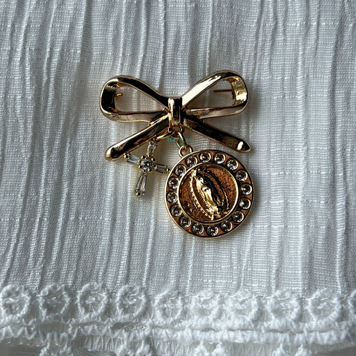 Gold bow brooch inspired by the Virgin Mary with luminous detailing