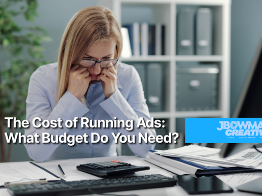 Woman in office looks worried, surrounded by papers and a calculator. Text: "The Cost of Running Ads: What Budget Do You Need?"