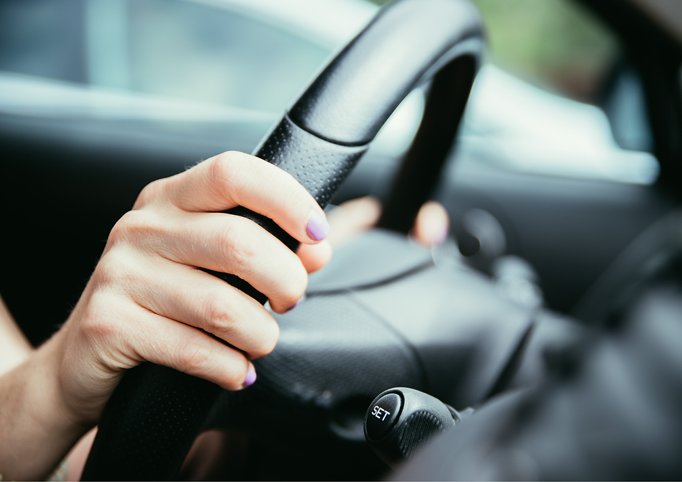 A woman using the steering wheel of a car.